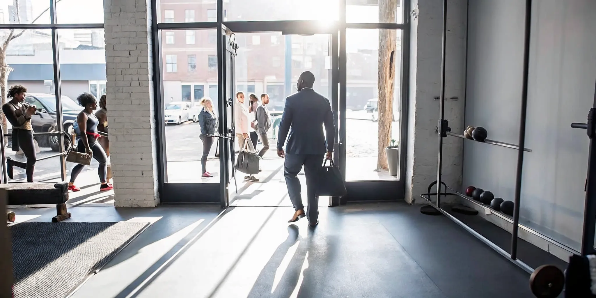 Busy professional entering a boutique fitness studio in Williamsburg Brooklyn with natural light and workout equipment